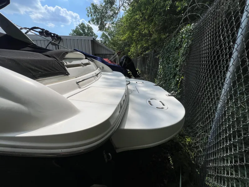 Slide: The Image of 2000 Sea Ray 280 Bowrider boat docked near a chain-link fence under a sunny sky. - 3