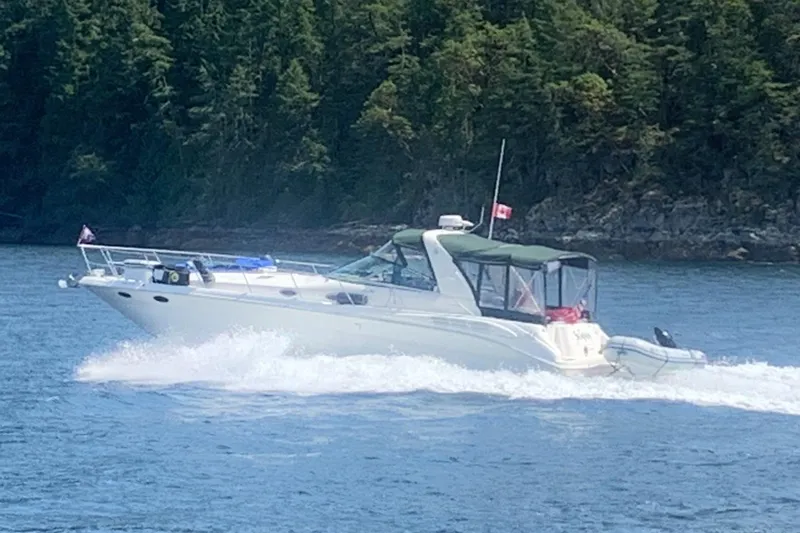 The Image of 1999 Sea Ray 400 Sundancer cruising on water near forested shoreline. - 0