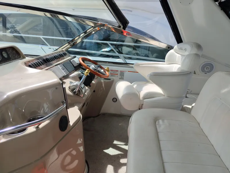 Slide: The Image of 1999 Sea Ray 400 Sundancer cockpit with white leather seating and wooden steering wheel. - 15