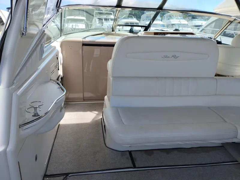Slide: The Image of 1999 Sea Ray 400 Sundancer interior with white seating and helm, docked in marina. - 21