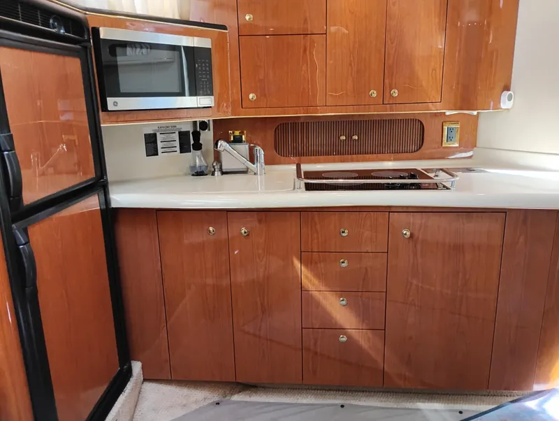 Slide: The Image of 1999 Sea Ray 400 Sundancer yacht kitchen with wood cabinets, microwave, and sink. - 28