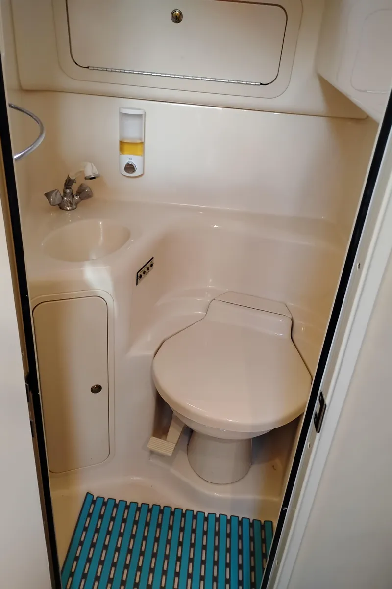 Slide: The Image of 1999 Sea Ray 400 Sundancer bathroom with sink, toilet, and striped mat. - 49