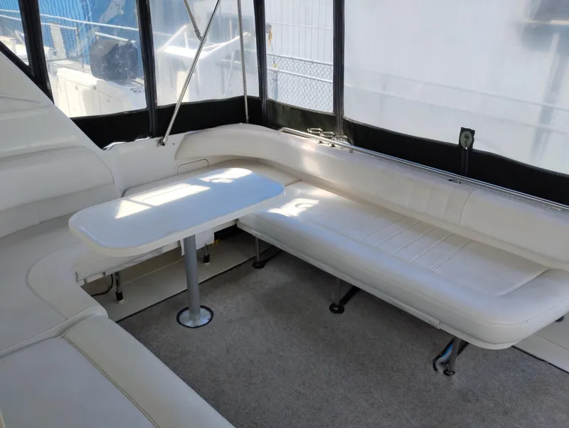 Slide: The Image of 1999 Sea Ray 400 Sundancer interior with white seating and table, enclosed by clear panels. - 7