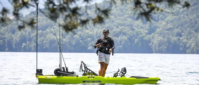 Slide: The Image of Person fishing on a 2023 Bonafide P127 kayak in a scenic lake setting. - 7