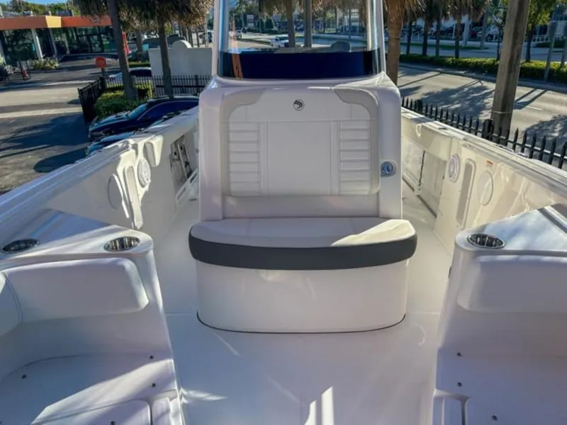 Slide: The Image of 2025 Edgewater 262CC boat interior with seating and cup holders in a sunny marina. - 16