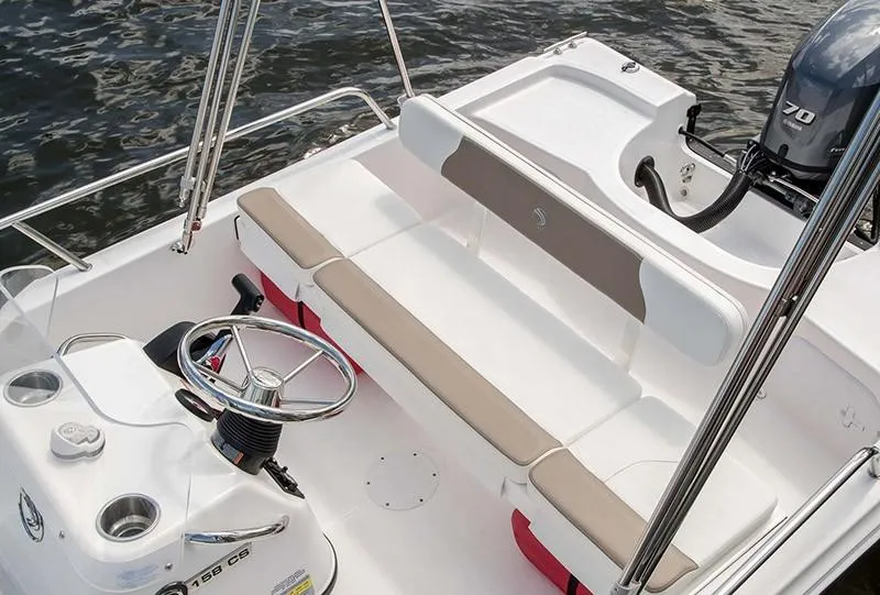 Slide: The Image of 2024 Edgewater 158CS boat interior with steering wheel and seating, on calm water. - 3