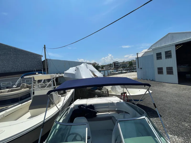 Slide: The Image of 2004 Cobalt 226 boat docked near storage buildings under a clear blue sky. - 20