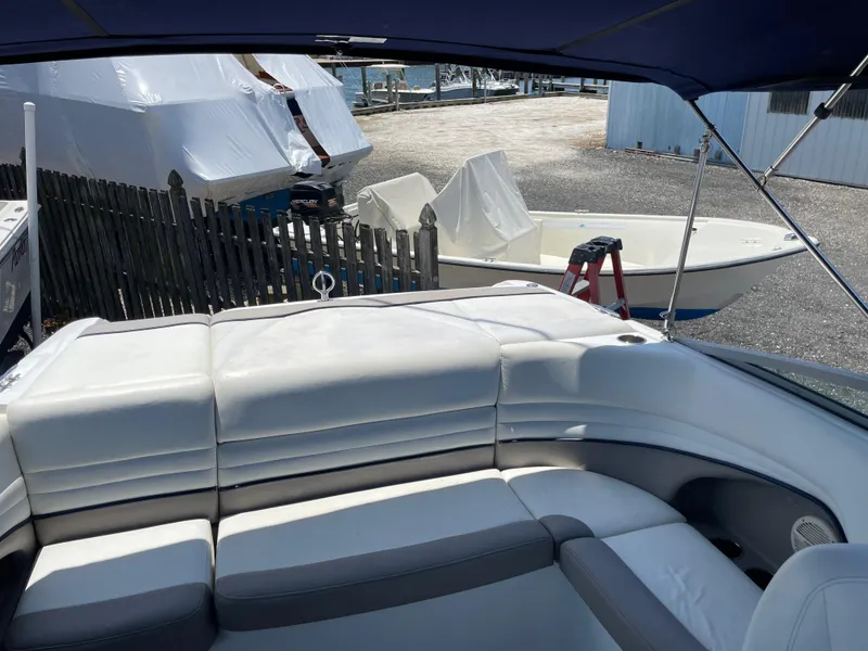 Slide: The Image of 2004 Cobalt 226 boat interior with white leather seating, docked near covered boats. - 23
