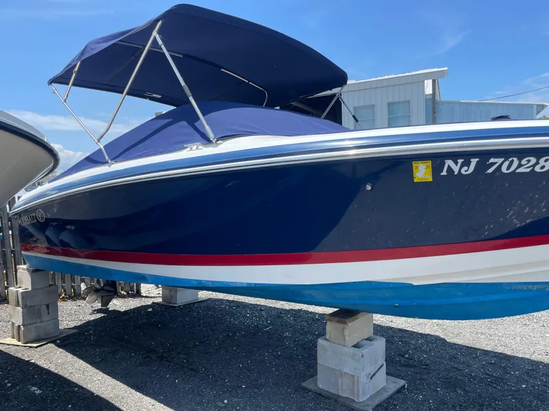 Slide: The Image of 2004 Cobalt 226 boat with blue cover, docked on blocks, sunny day. - 29