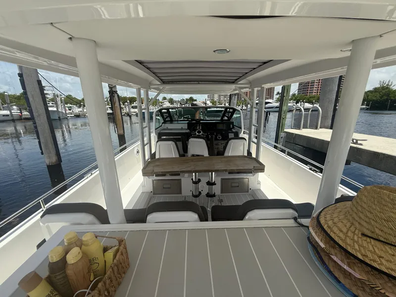 Slide: The Image of 2017 Axopar 37 Sun Top boat interior with seating and table, docked at marina. - 13