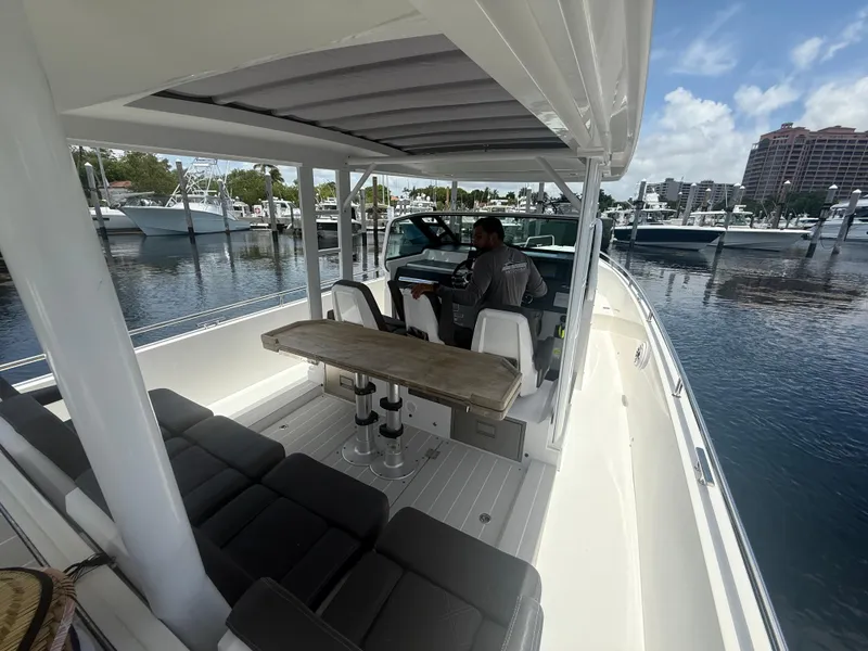 Slide: The Image of 2017 Axopar 37 Sun Top boat interior with seating and table, docked at marina. - 14