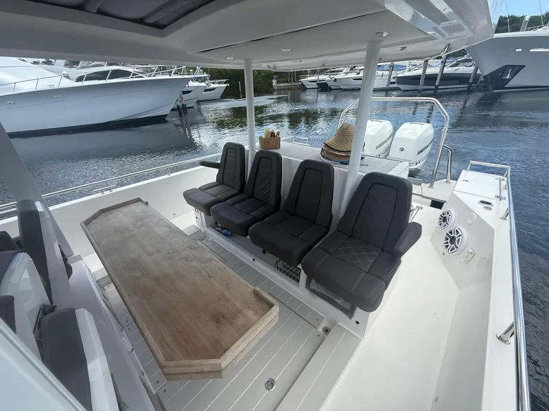 Slide: The Image of 2017 Axopar 37 Sun Top boat interior with seating and table, docked near other boats. - 16
