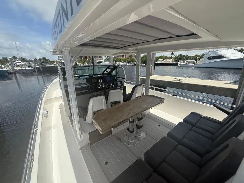 Slide: The Image of 2017 Axopar 37 Sun Top boat interior with seating and helm, docked at marina. - 17