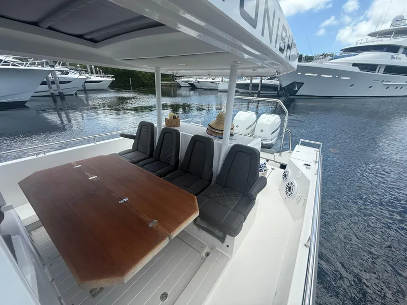 Slide: The Image of 2017 Axopar 37 Sun Top boat with seating and table, docked near luxury yachts. - 18