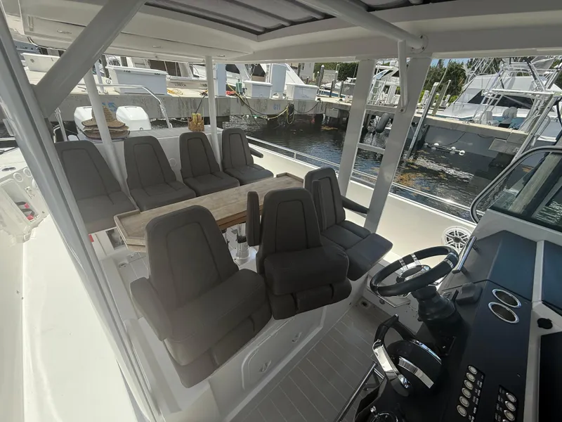 Slide: The Image of 2017 Axopar 37 Sun Top boat interior with seating and steering wheel, docked at marina. - 19