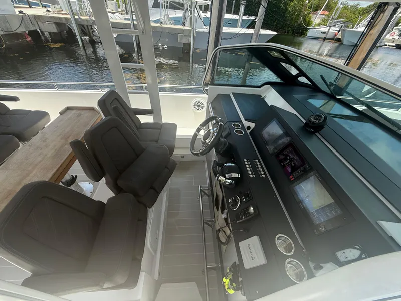 Slide: The Image of 2017 Axopar 37 Sun Top helm with modern controls and seating, docked by the water. - 21