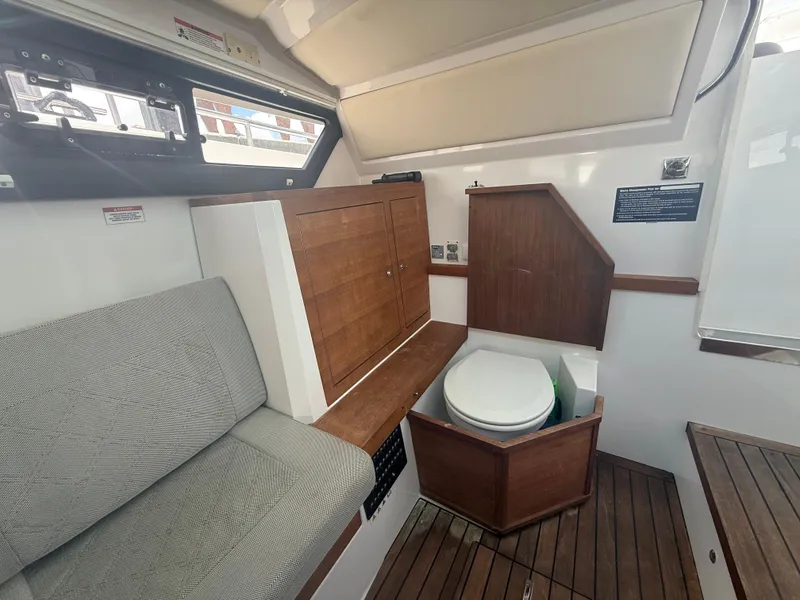 Slide: The Image of 2017 Axopar 37 Sun Top interior with wooden cabinetry, seating, and compact toilet. - 28