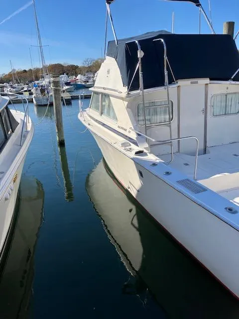 Slide: The Image of 1974 Bertram 28 Flybridge boat docked in a marina, clear blue sky. - 1