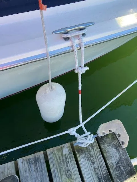 Slide: The Image of 1974 Bertram 28 Flybridge docked with fender and rope, wooden pier visible. - 10