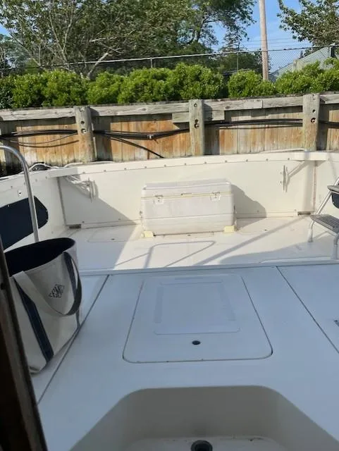 Slide: The Image of 1974 Bertram 28 Flybridge boat deck with cooler, surrounded by wooden fence and greenery. - 15