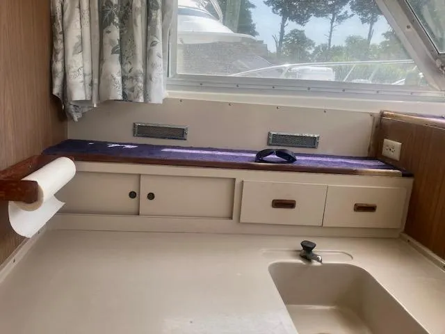 Slide: The Image of 1974 Bertram 28 Flybridge interior with sink, storage, and window view. - 5
