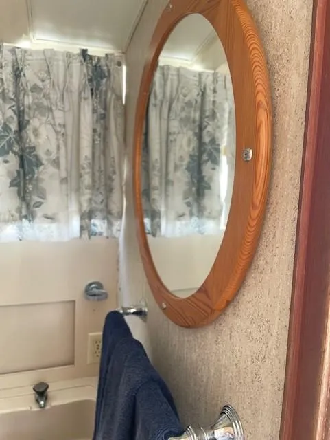 Slide: The Image of 1974 Bertram 28 Flybridge bathroom with round mirror and floral curtains. - 7