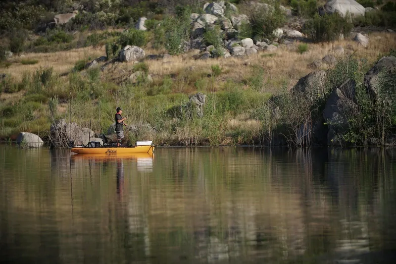 Slide: The Image of Angler fishing on a 2025 Hobie Pro Angler 12 kayak in a serene lake setting. - 5