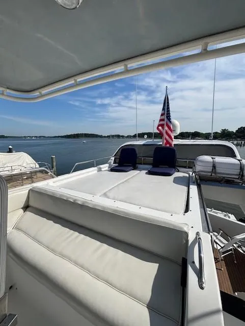 Slide: The Image of Luxury yacht deck with seating, American flag, and scenic waterfront view. Johnson High Tech Euro 56, 1994. - 12