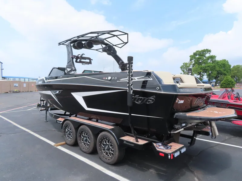Slide: The Image of 2023 Tigé 24RZX boat on trailer, parked in a lot under a clear sky. - 2