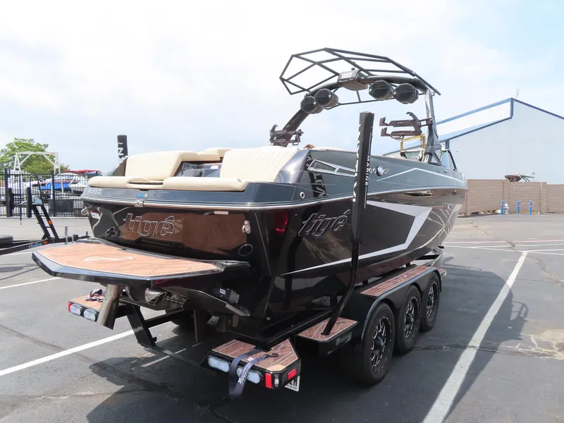 Slide: The Image of 2023 Tigé 24RZX boat on trailer, black exterior, parked in a lot. - 3
