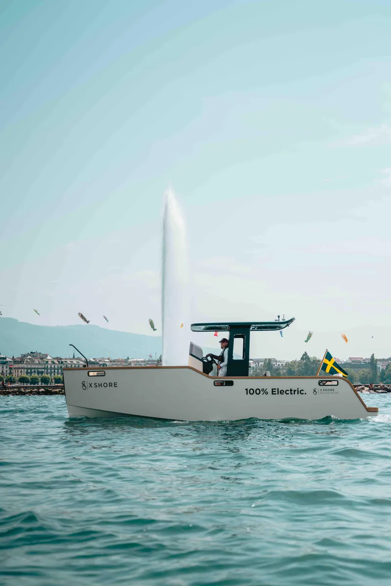 Slide: The Image of 2023 X Shore Eelex 8000 electric boat on water with Swedish flag, fountain in background. - 7