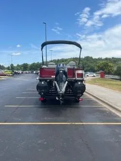 Slide: The Image of 2024 Regency 250 DL3 pontoon boat parked in a lot under a clear blue sky. - 2