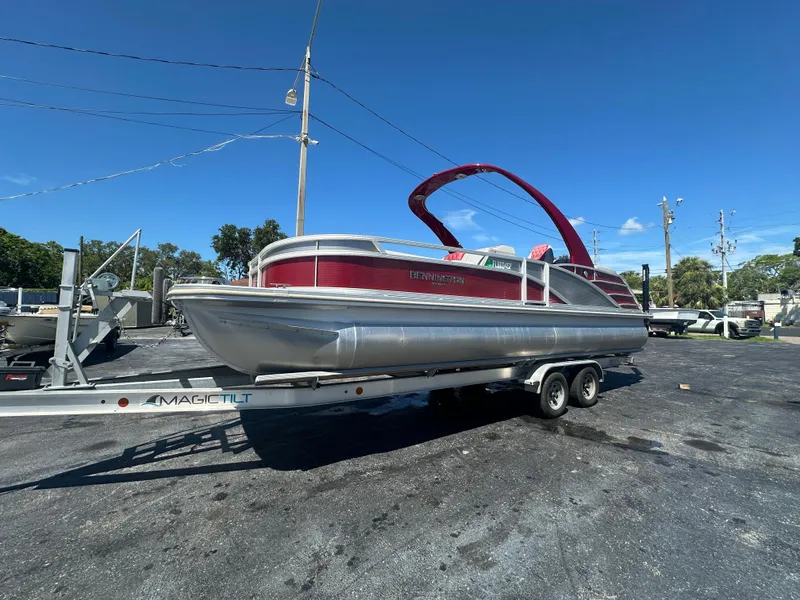 Slide: The Image of 2020 Bennington R 24 RTFBA pontoon boat on trailer under clear blue sky. - 1