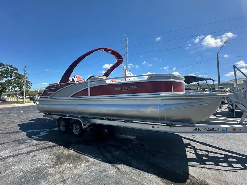 Slide: The Image of 2020 Bennington R 24 RTFBA pontoon boat on trailer under clear blue sky. - 3