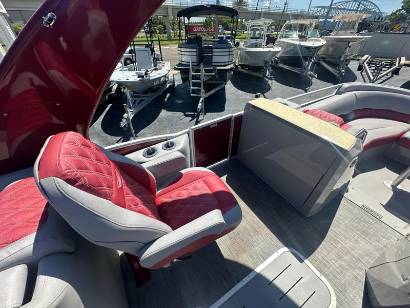 Slide: The Image of 2020 Bennington R 24 RTFBA pontoon boat interior with red and gray seating, docked near other boats. - 31