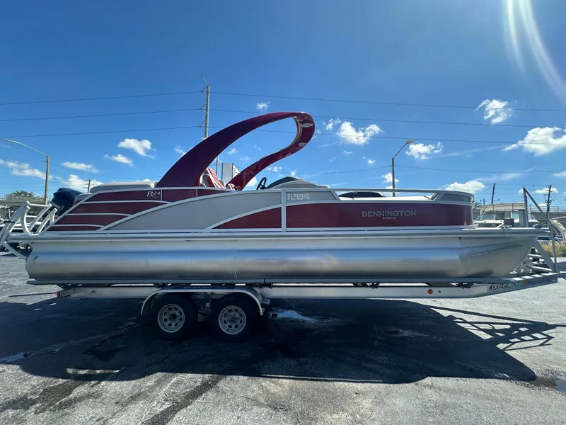 Slide: The Image of 2020 Bennington R 24 RTFBA pontoon boat on trailer under clear blue sky. - 4