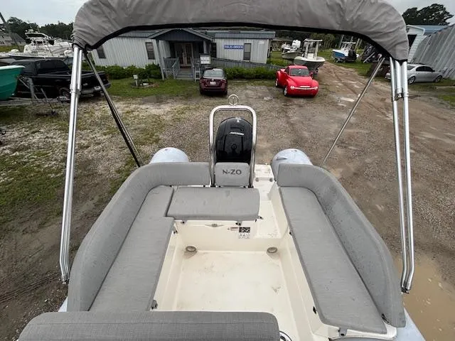 Slide: The Image of 2023 Zodiac NZO-680 boat with gray seating and canopy, parked near vehicles. - 15