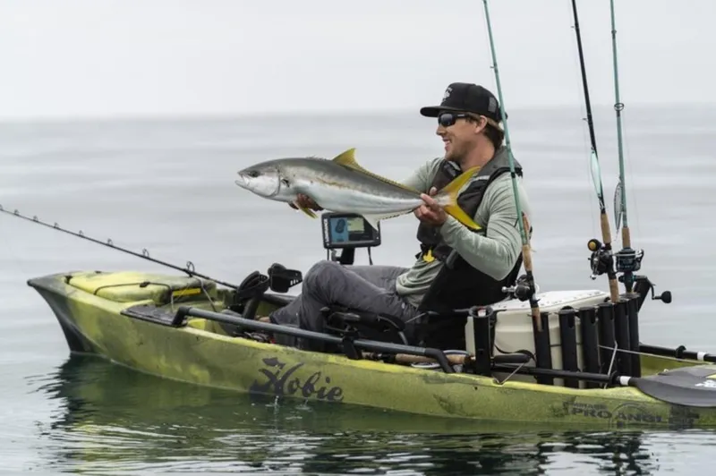 Slide: The Image of Man fishing on Hobie Mirage Pro Angler 12 kayak, holding a large fish, 2025 model. - 1