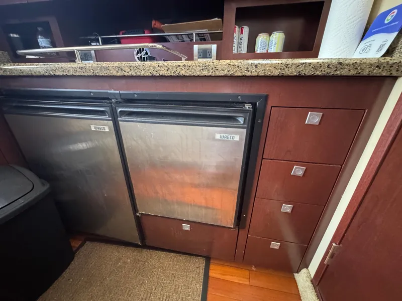 Slide: The Image of Interior of 2007 Sea Ray 360 Sedan with compact kitchen appliances and wooden cabinetry. - 38