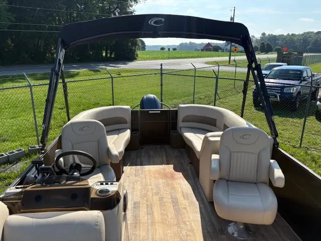Slide: The Image of 2018 Crest I 220 SLC pontoon boat with beige seating and canopy, parked outdoors. - 3