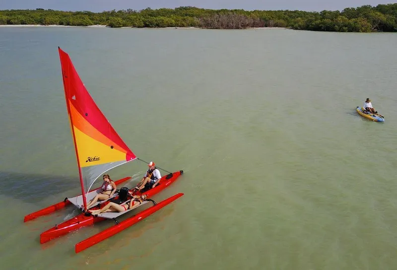 Slide: The Image of 2025 Hobie Mirage Tandem Island sailing on calm waters with vibrant sail. - 5