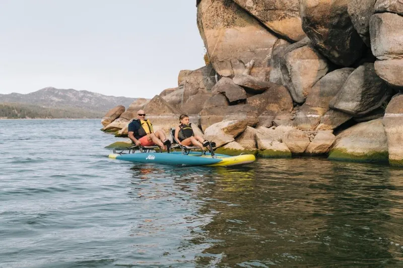 Slide: The Image of Two people kayaking on a Hobie iTrek 14 Duo near rocky shoreline, 2025 model. - 4