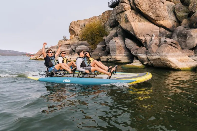 Slide: The Image of Four people enjoying a ride on a 2025 Hobie iTrek Fiesta near rocky cliffs. - 2