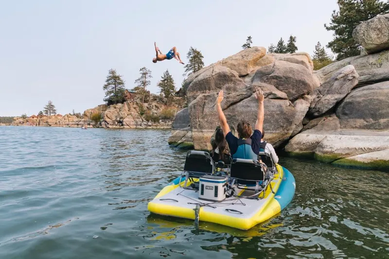 Slide: The Image of 2025 Hobie iTrek Fiesta on lake, people enjoying water activities near rocky shore. - 4