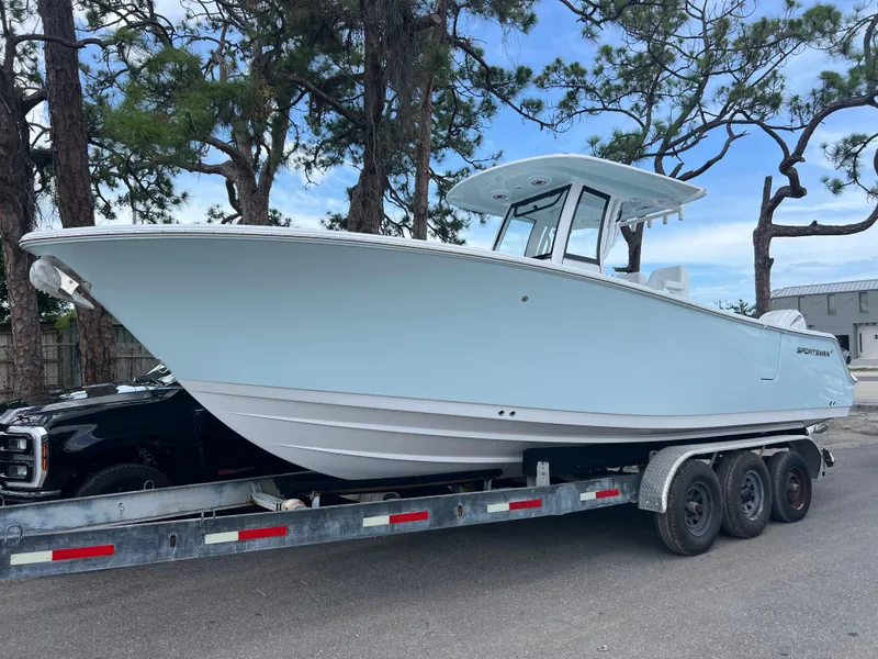 The Image of 2025 Sportsman Open 262 Center Console boat on trailer, parked near trees. - 0