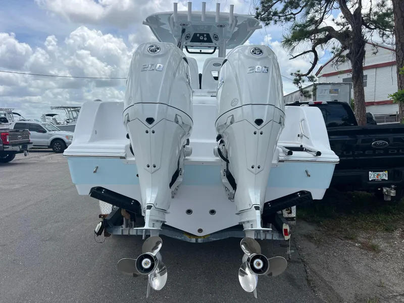 Slide: The Image of 2025 Sportsman Open 262 Center Console with twin outboard engines, parked outdoors. - 5