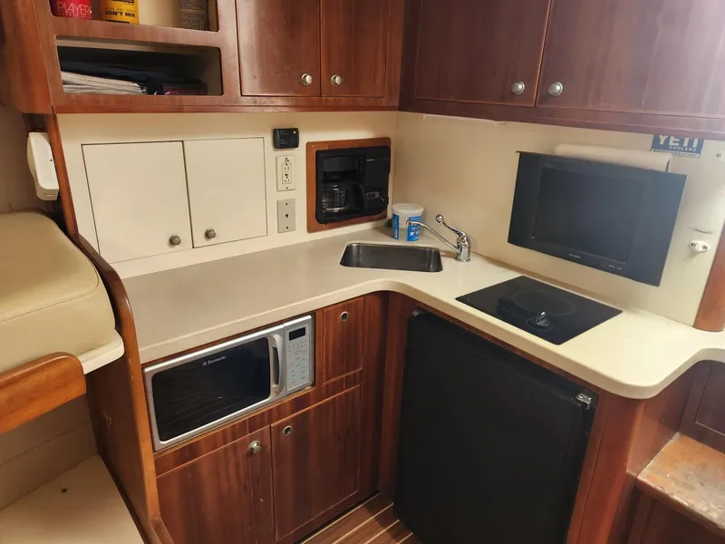 Slide: The Image of 2003 Luhrs 30 Open boat kitchen with microwave, sink, and stove. - 19