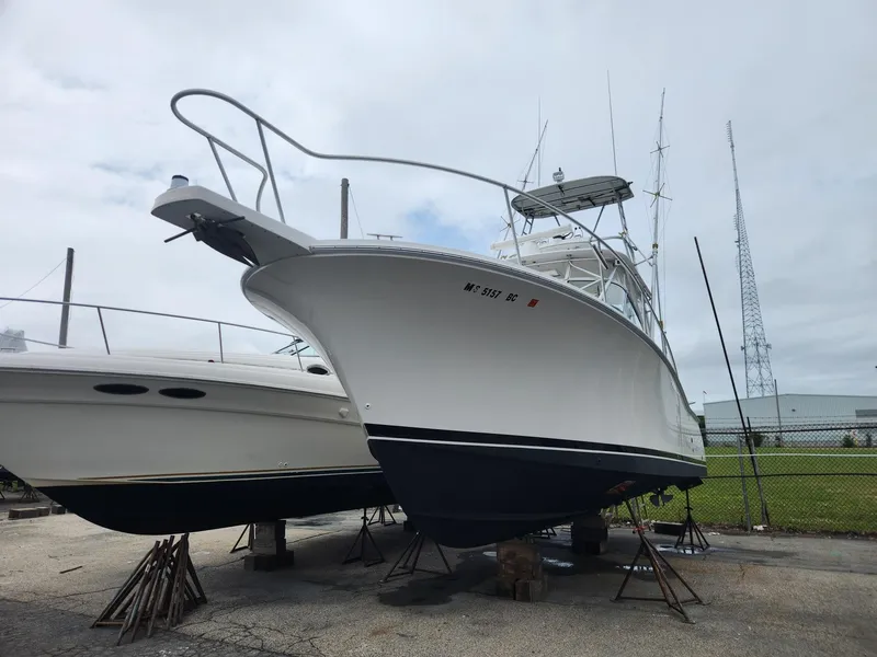 Slide: The Image of 2003 Luhrs 30 Open boat on stands, marina background, overcast sky. - 3
