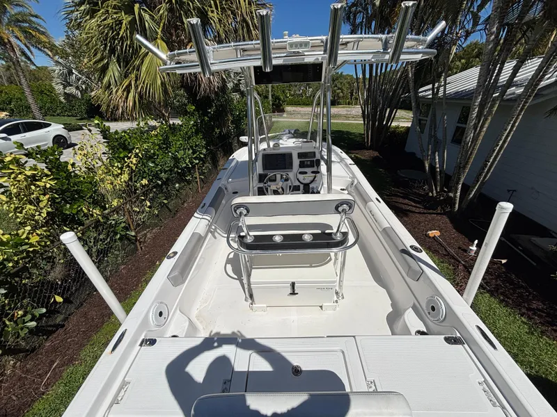 Slide: The Image of 2013 SeaHunter 24 Bay boat with center console and rod holders, surrounded by lush greenery. - 13