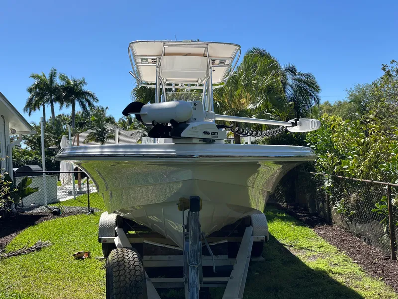 Slide: The Image of 2013 SeaHunter 24 Bay boat on trailer, surrounded by lush greenery and palm trees. - 2